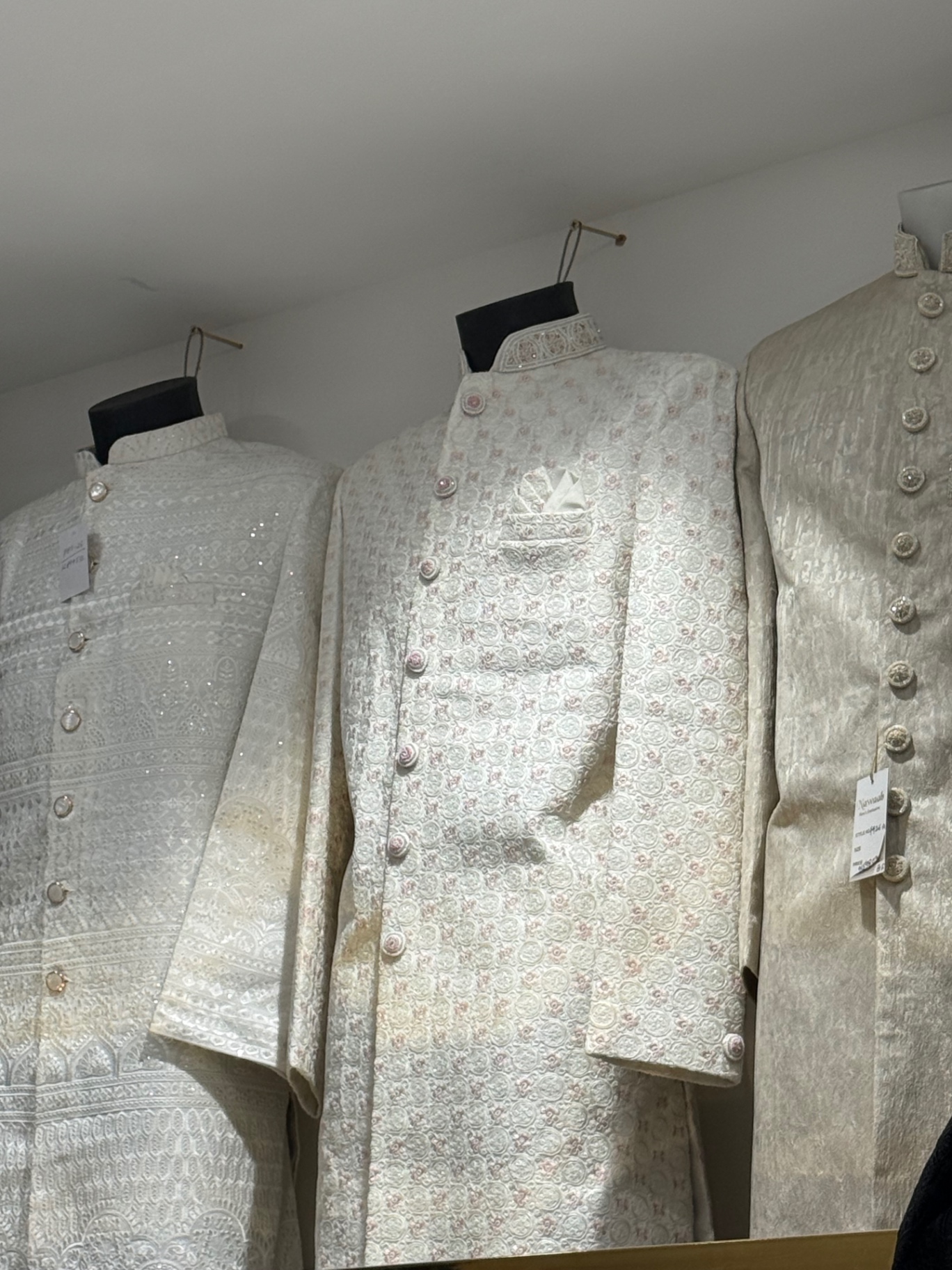 Ivory embroidered sherwanis hanging in the showroom